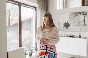 Young woman managing diabetes indoors with an insulin pen in a bright living room.